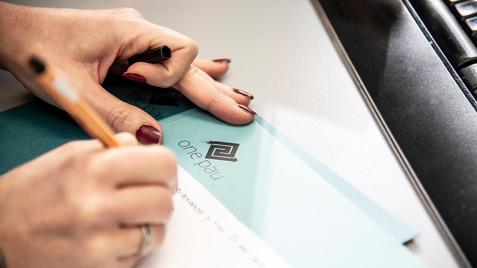 eine weibliche Mitarbeiterin des Steuerberater Studios in Bozen ONEPAU schreibt den Namen eines Kunden auf einen Ordner